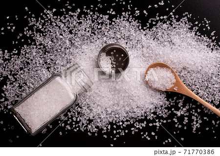 Salt shaker with salt and wooden spoon top view. 71770386