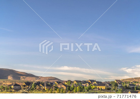 Sunny day view of homes in a neighborhood with mountain and blue sky background 71771476