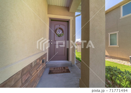 Small porch and brown front door decorated with wreath at the facade of a home Small porch and brown front door decorated with wreath at the facade of a home 71771494