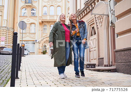 Woman walking arm in arm with her dear senior mother 71775526