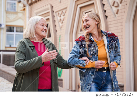 Woman walking arm in arm with her dear senior mother 71775527