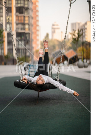 Young woman rides on a swing at the playground. Young woman rides on a swing at the playground. 71775805
