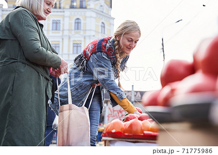Mother and her lovely daughter holding shopper bag by two handles Mother and her lovely daughter holding shopper bag by two handles 71775986