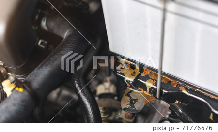 Battery shelf peeling black paint and rust in car engine, Distilled water leak, Engine checking concept. Battery shelf peeling black paint and rust in car engine, Distilled water leak, Engine checking concept. 71776676