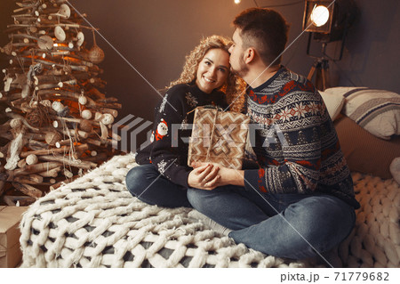 Elegant couple sitting at home near christmas tree 71779682