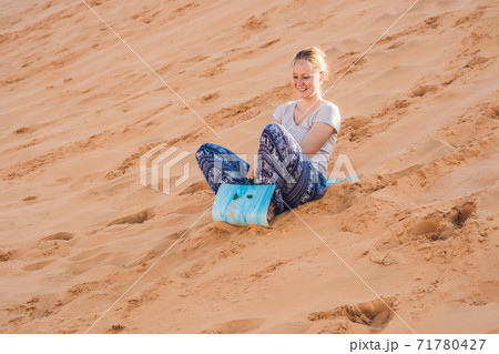 Young woman rolls on a toboggan in the sledge in the desert Young woman rolls on a toboggan in the sledge in the desert 71780427