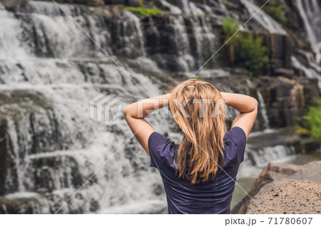 Young woman hiker, tourist on the background of Amazing Pongour Waterfall is famous and most beautiful of fall in Vietnam. Not far from Dalat city estimate 45 Km. Dalat, Vietnam 71780607