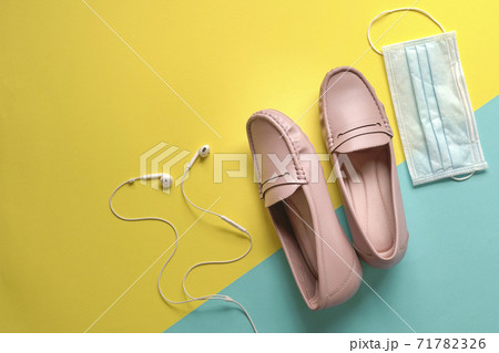 Stylish women shoes, ear phones and medical face mask on yellow and blue background. 71782326