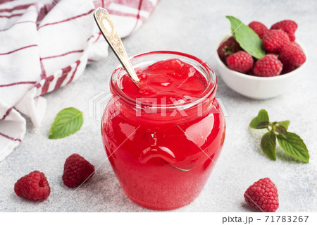 Homemade raspberry jam in a glass jar and fresh raspberries with mint on a grey concrete background. Copy space Homemade raspberry jam in a glass jar and fresh raspberries with mint on a grey concrete background. Copy space 71783267