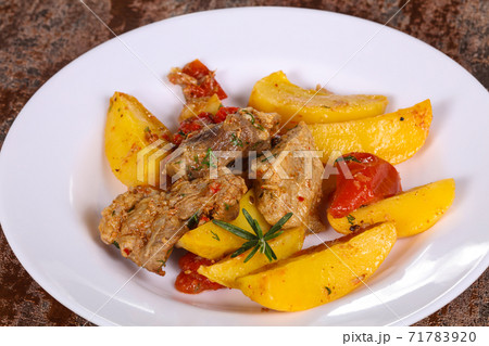 Baked pork meat with potao and tomato 71783920
