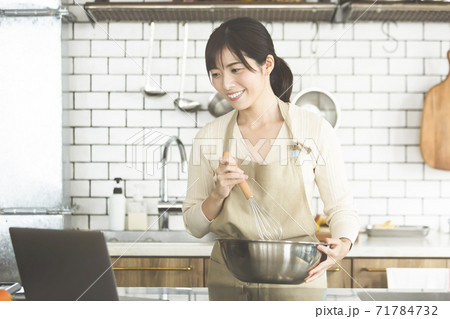 パソコンを見ながら料理を作る女性 パソコンを見ながら料理を作る女性 71784732