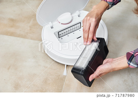 Woman cleans dust container in robotic vacuum cleaner. Household appliances service 71787980