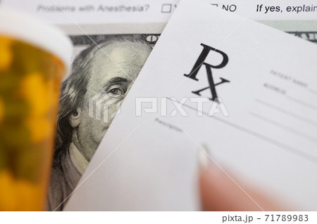 Dollar bill and doctors prescription are on doctors table in clinic closeup Dollar bill and doctors prescription are on doctors table in clinic closeup 71789983