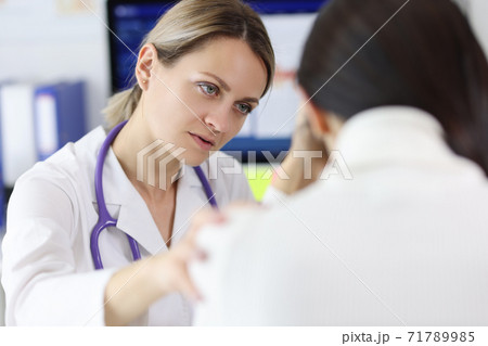 Doctor lying her hand on shoulder of upset patient at clinic 71789985