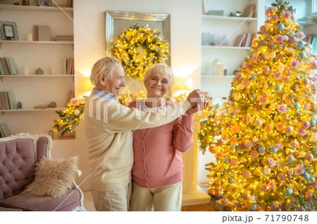 Senior couple dancing near christmas tree and looking happy 71790748