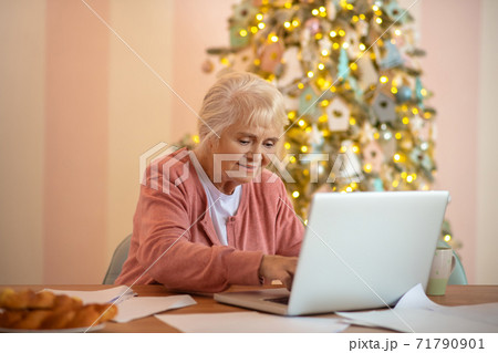 Elderly woman working on a laptop and looking involved 71790901