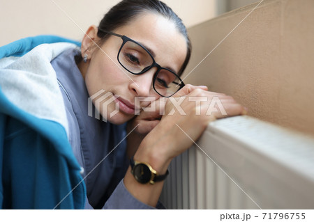 Sad woman holds her hands on battery. Sad woman holds her hands on battery. 71796755