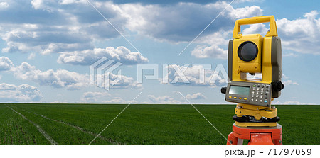 Theodolite on a background of green field 71797059