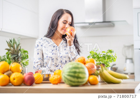Woman in the kitchen enjoying the aroma of fresh grapefruit 71800717