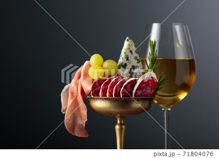 Wine, blue cheese, dry-cured sausage, grapes, and rosemary on a black background. Wine, blue cheese, dry-cured sausage, grapes, and rosemary on a black background. 71804076