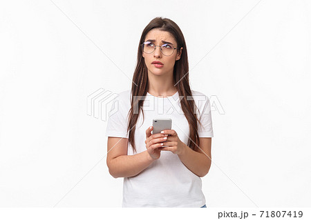 Communication, technology and lifestyle concept. Portrait of troubled and concerned young woman worried for friend, sending text message if shes okay and thinking, look up nervous, hold mobile phone Communication, technology and lifestyle concept. Portrait of troubled and concerned young woman worried for friend, sending text message if shes okay and thinking, look up nervous, hold mobile phone 71807419