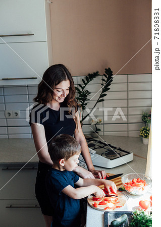 Mom and young son cut vegetables for salad in the kitchen 71808331