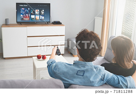 Young couple watching TV on sofa Young couple watching TV on sofa 71811288