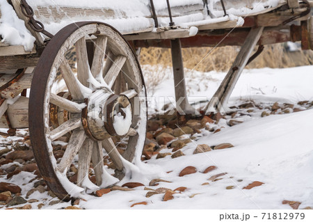 An old wooden wagon with rusty wheels dusted with snow in winter An old wooden wagon with rusty wheels dusted with snow in winter 71812979