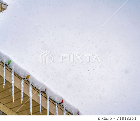 Clear Panorama Snow covered roof with icicles and colorful lights against a cloudy sky Clear Panorama Snow covered roof with icicles and colorful lights against a cloudy sky 71813251
