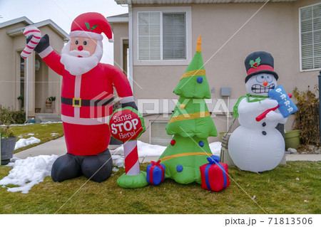 Inflatable Christmas decorations on a grassy yard with snow in winter Inflatable Christmas decorations on a grassy yard with snow in winter 71813506