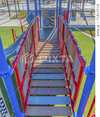 Playground equipment with a bridge and slide against vibrant green lawn Playground equipment with a bridge and slide against vibrant green lawn 71813518