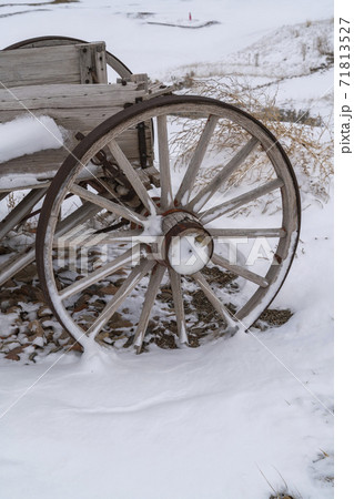 Wheel of an old wooden cart against a rocky snow covered terrain in winter Wheel of an old wooden cart against a rocky snow covered terrain in winter 71813527