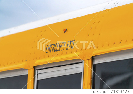 Close up of the exterior of a yellow school bus with an Emergency Exit sign 71813528
