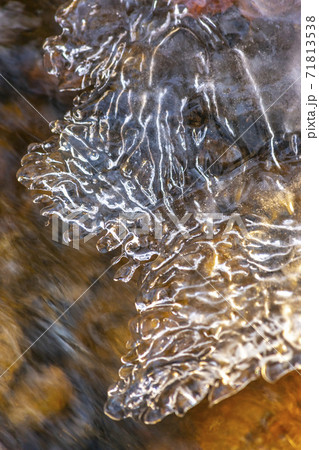 Close up of translucent frozen water on a rocky stream during winter Close up of translucent frozen water on a rocky stream during winter 71813538