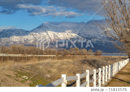 Construction site near a lake viewed on the other side of a white picket fence 71813570