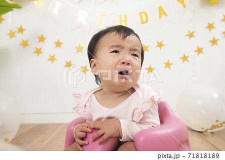 誕生日会で大泣きする1歳の赤ちゃんの写真素材