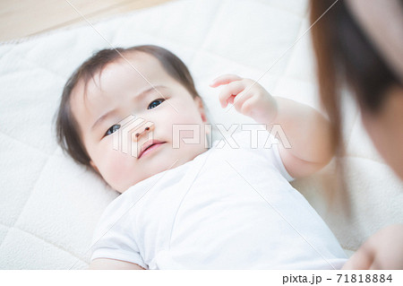 赤ちゃんを布団に寝かせる女性 71818884