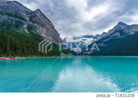 Canoeing on Lake Louise in summer day. Tourists enjoy leisure water activities on the turquoise color lake in Banff National Park, Alberta, Canada. Canoeing on Lake Louise in summer day. Tourists enjoy leisure water activities on the turquoise color lake in Banff National Park, Alberta, Canada. 71821226