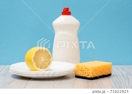 Bottles of dishwashing liquid, sponge, plates and lemon on blue background. 71822925