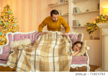 Caring husband covering his napping wife with a plaid 71823762