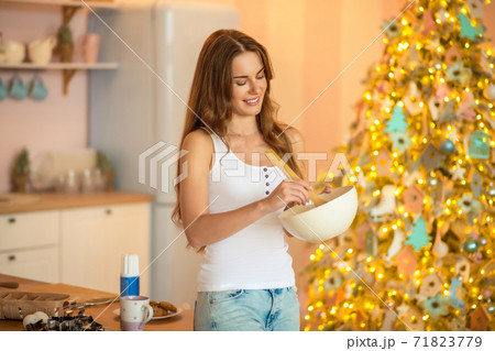 Pretty woman in white tshirt stirring something in a bowl and smiling Pretty woman in white tshirt stirring something in a bowl and smiling 71823779