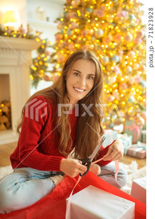 Dark-haired young woman packing christmas gifts and looking happy Dark-haired young woman packing christmas gifts and looking happy 71823928