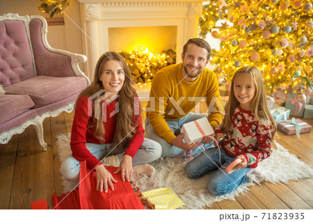 Young family sitting on the floor and packing christmas gifts 71823935
