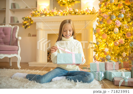 Blonde cute girl looking happy while holding her gift box 71823991