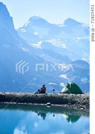 Male tourist enjoying mountains scenery near tent. 71825451