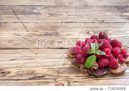 A pile of fresh juicy raspberries on a wooden Board, copy space. A pile of fresh juicy raspberries on a wooden Board, copy space. 71826068