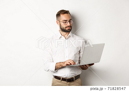 Business. Serious manager working on laptop, standing over white background Business. Serious manager working on laptop, standing over white background 71828547