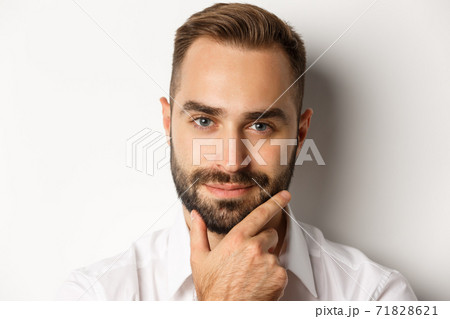 Emotions and people concept. Headshot of handsome thoughtful man smiling satisfied, touching beard and thinking, standing over white background 71828621