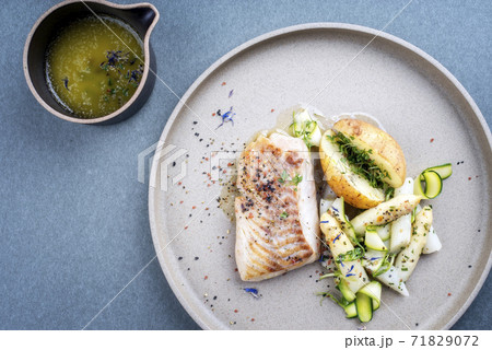 German fried skrei cod fish filet with white asparagus tips and roast potatoes  71829072