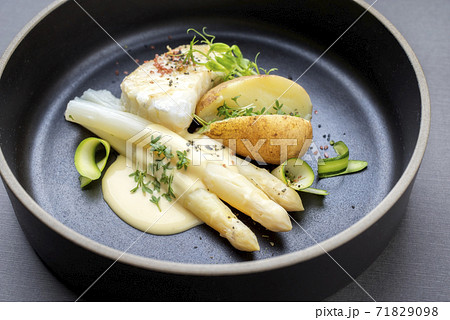 German fried cod fish filet with white asparagus in sauce hollandaise und roast potatoes German fried cod fish filet with white asparagus in sauce hollandaise und roast potatoes 71829098